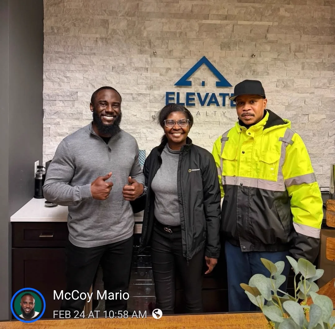 Mario giving a thumbs up with two clients at the Elevate Realty office